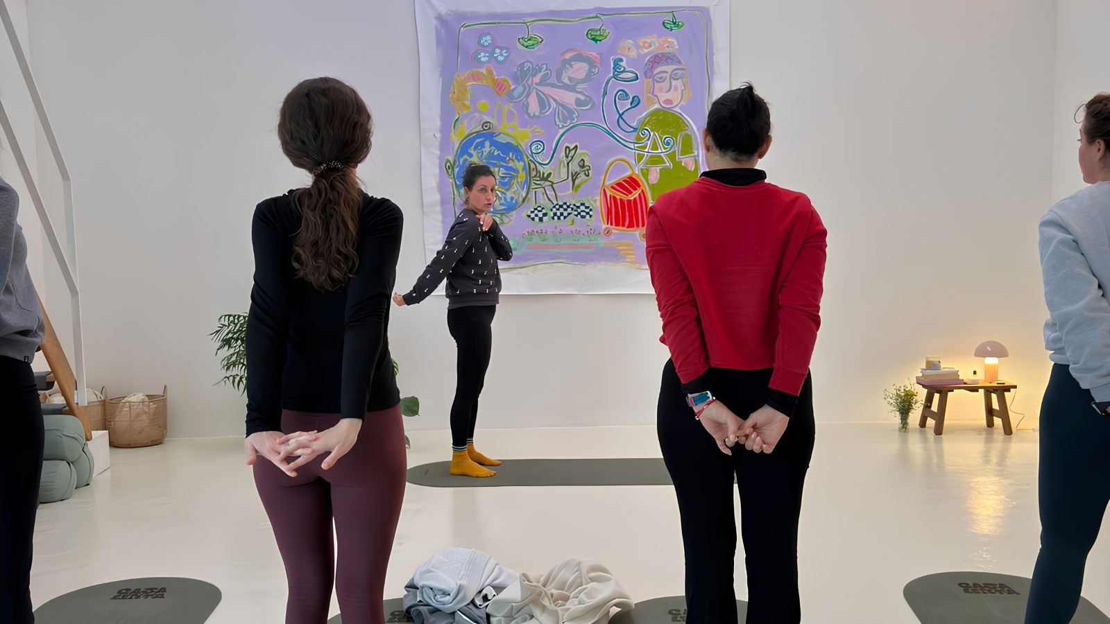 Profesora de yoga guiando a un grupo de alumnas de pie sobre sus esterillas durante una clase